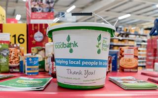 collection bucket for foodbank on table with leaflets in a supermarket
